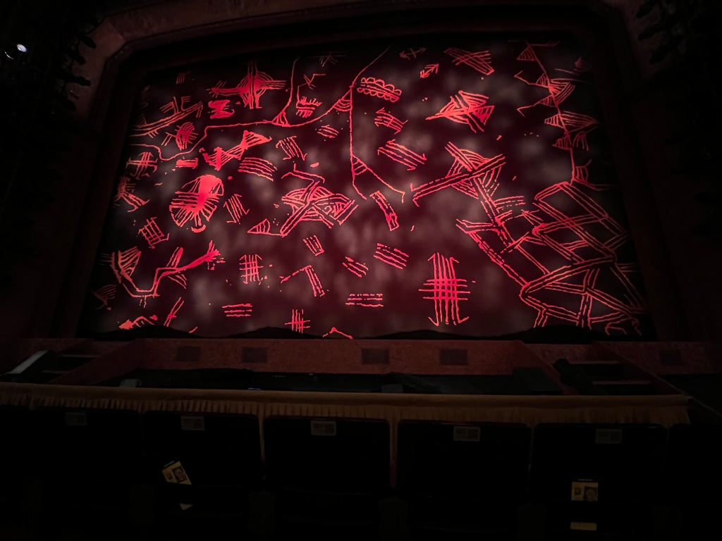 A photo of the stage at the lion king before the show. A red African  patterned safety curtain.